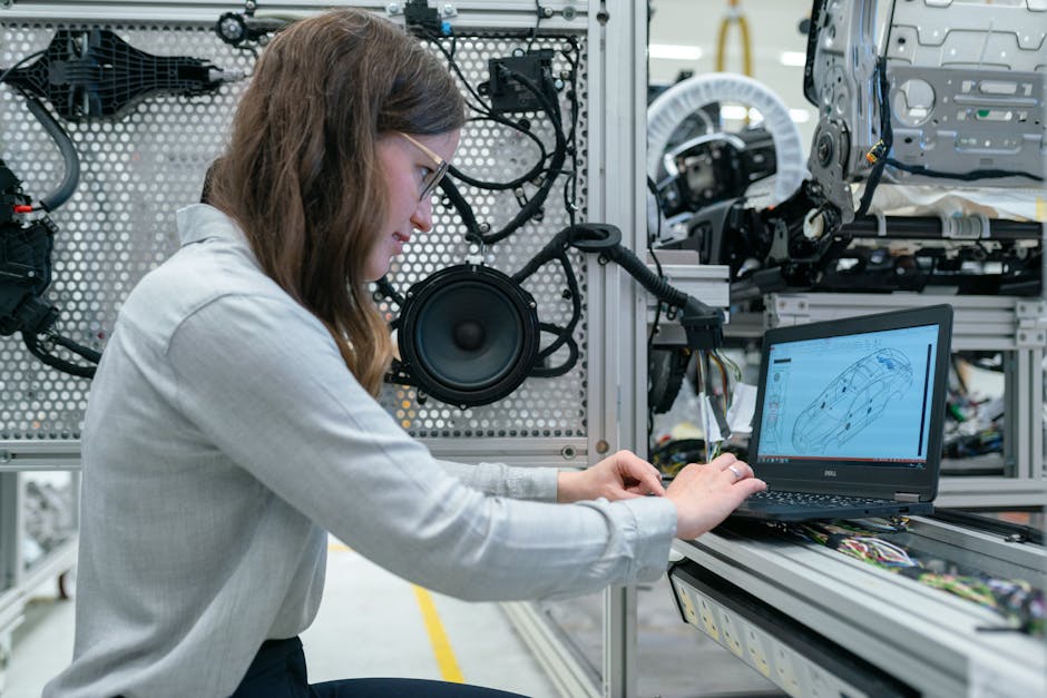 Woman conducting engineering research in a sound system workshop using a laptop