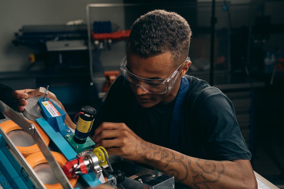 Focused young engineer wearing safety glasses adjusting machinery with precision in an industrial setting
