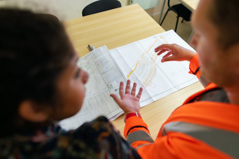 Two engineers reviewing construction blueprints on a table in an office setting